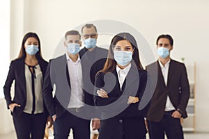 Responsible young company manager with group of workers all wearing face masks at work