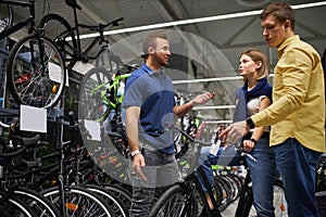 Responsive good-looking consultant and buyers in bicycles store