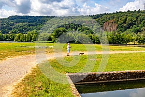 Rest area next to Lake Echternach on small recreational peninsula in park, woman walking with her dog