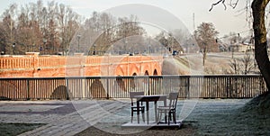 Rest area by the old red brick bridge, on a sunny winter day without snow, with a table and two chairs, Kuldiga, Latvia