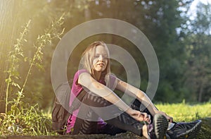 Rest while hiking. young caucasian woman hiker sitting in forest relaxing during hike. woman with backpack