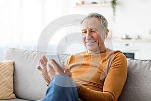 Happy mature man using cellphone wearing headphones