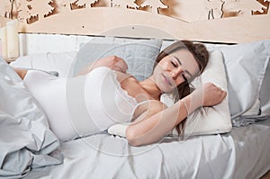 Rest, sleeping, comfort and people concept - young woman stretching in bed at home bedroom.