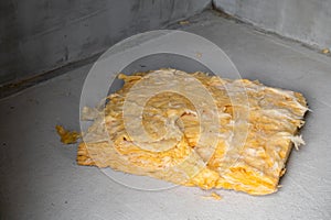 The rest of the yellow glass wool lies on the concrete floor, close-up. Universal insulation and soundproofing material