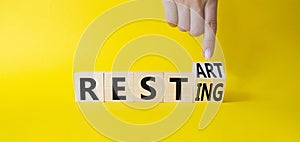 Restart and resting symbol. Businessman hand Turnes cubes and changes word Resting to Restart. Beautiful yellow background.