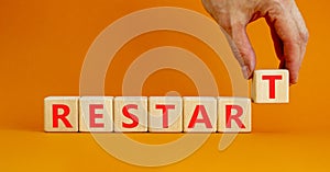 Restart and start symbol. The concept word Restart on wooden cubes. Beautiful orange table, orange background, copy space.