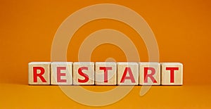 Restart and start symbol. The concept word Restart on wooden cubes. Beautiful orange table, orange background, copy space.