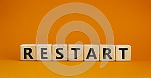 Restart and start symbol. The concept word Restart on wooden cubes. Beautiful orange table, orange background, copy space.