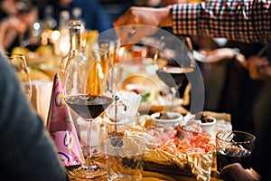 Restaurant or bar table with plates of appetizers and wine. People talking on background. Toned picture