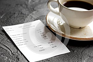 Restaurant bill, card and coffee on dark table background