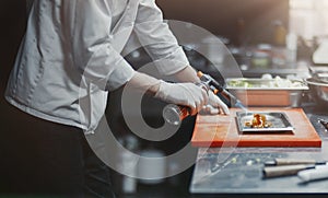 Restaurant Chef cook preparing salmon filet flambe in open kitchen