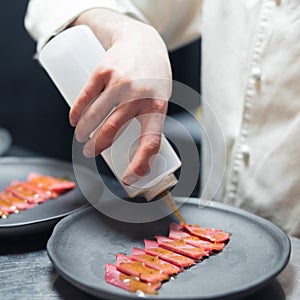 Restaurant Chef cook preparing tuna striped filet and pouring fish with oil sause