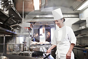 Restaurant, cooking and a woman chef in the kitchen for luxury hospitality or preparation of a gourmet meal. Food