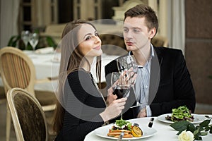 restaurant, couple and holiday concept - smiling couple drinking red wine.