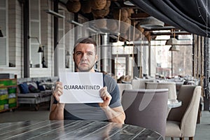 Restaurant director is holding white sheet of paper with word Quarantined