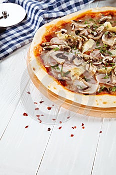 Close up view on pizza on white wooden background with ingridients.