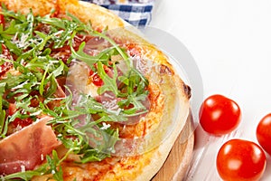 Close up view on pizza on white wooden background with ingridients.