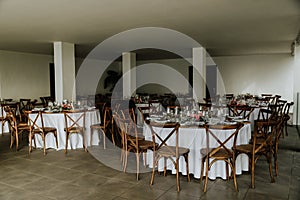 Restaurant hall with white tables and wooden chairs decorated for an event