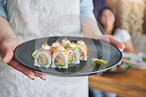 Restaurant, hands and closeup of sushi on a plate for luxury, healthy and authentic Asian cuisine. Platter, fine dining