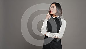 Restaurant hostess being thoughtful over grey background