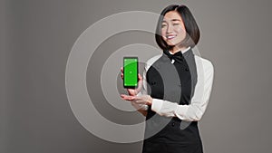 Restaurant hostess presenting smartphone with greenscreen