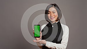 Restaurant hostess presenting smartphone with greenscreen