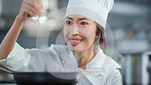 Restaurant Kitchen: Portrait of Asian Female Chef Fries Uses Pan, Seasons Dish with Herbs and Spices