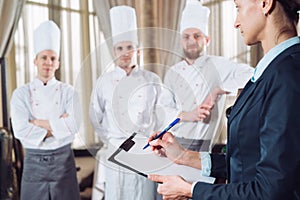 Restaurant manager and his staff in kitchen. interacting to head chef in commercial kitchen