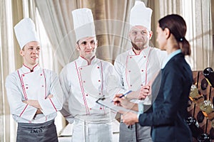 Restaurant manager and his staff in kitchen. interacting to head chef in commercial kitchen
