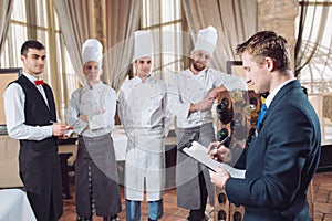 Restaurant manager and his staff in kitchen. interacting to head chef in commercial kitchen