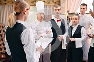 Restaurant manager and his staff in kitchen. interacting to head chef in commercial kitchen.