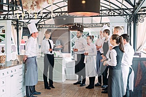 Restaurant manager and his staff in terrace. interacting to head chef in restaurant.