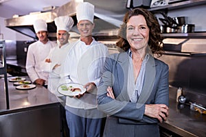 Restaurant manager posing in front of team of chefs