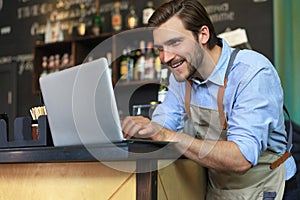 Restaurant manager working on laptop, counting profit