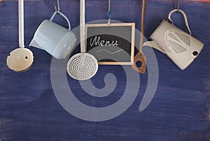 Restaurant menu with vintage kitchen utensils and message on blackboard, free copy space