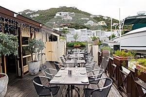 Restaurant open air in philipsburg, sint maarten. Terrace with tables, chairs and yacht in sea. Eating and dining outdoor. Summer