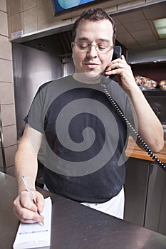 Restaurant owner writing take out order while on t