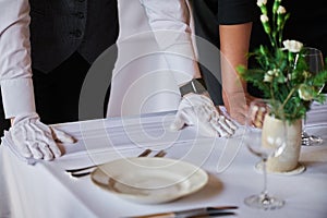 Restaurant personnel preparing the fine dining table.