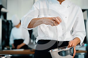 Restaurant professional kitchen: chef prepares a delicious dish, beats eggs in a bowl