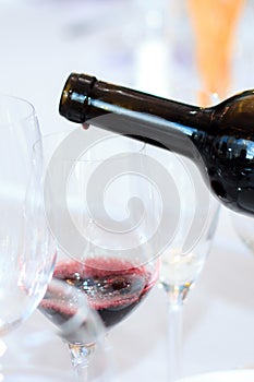 The process of pouring red wine from a bottle into a glass in a restaurant