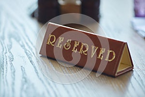 Restaurant reserved table sign. A brown reserved sign is on the table.