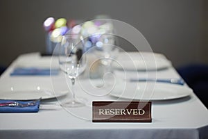 Restaurant reserved table sign with places setting and wine glasses ready for a party