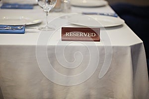 Restaurant reserved table sign with places setting and wine glasses ready for a party