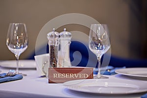 Restaurant reserved table sign with places setting and wine glasses ready for a party