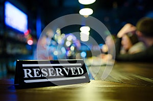 Restaurant reserved table sign standing on wooden table in bar