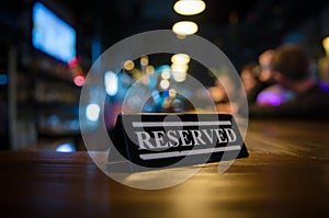 Restaurant reserved table sign standing on wooden table in bar