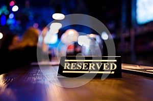 Restaurant reserved table sign standing on wooden table in bar