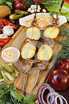 Restaurant service concept. Pork and vegetables cabobs on the cutting board with fresh herbs. Still life