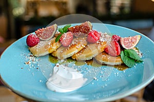 Restaurant sweet breakfast. Small pancakes with caramel cream and strawberries, figs, raspberries, fruit and meant on top.