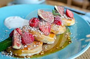 Restaurant sweet breakfast. Small pancakes with caramel cream and strawberries, figs, raspberries, fruit and mint on top.